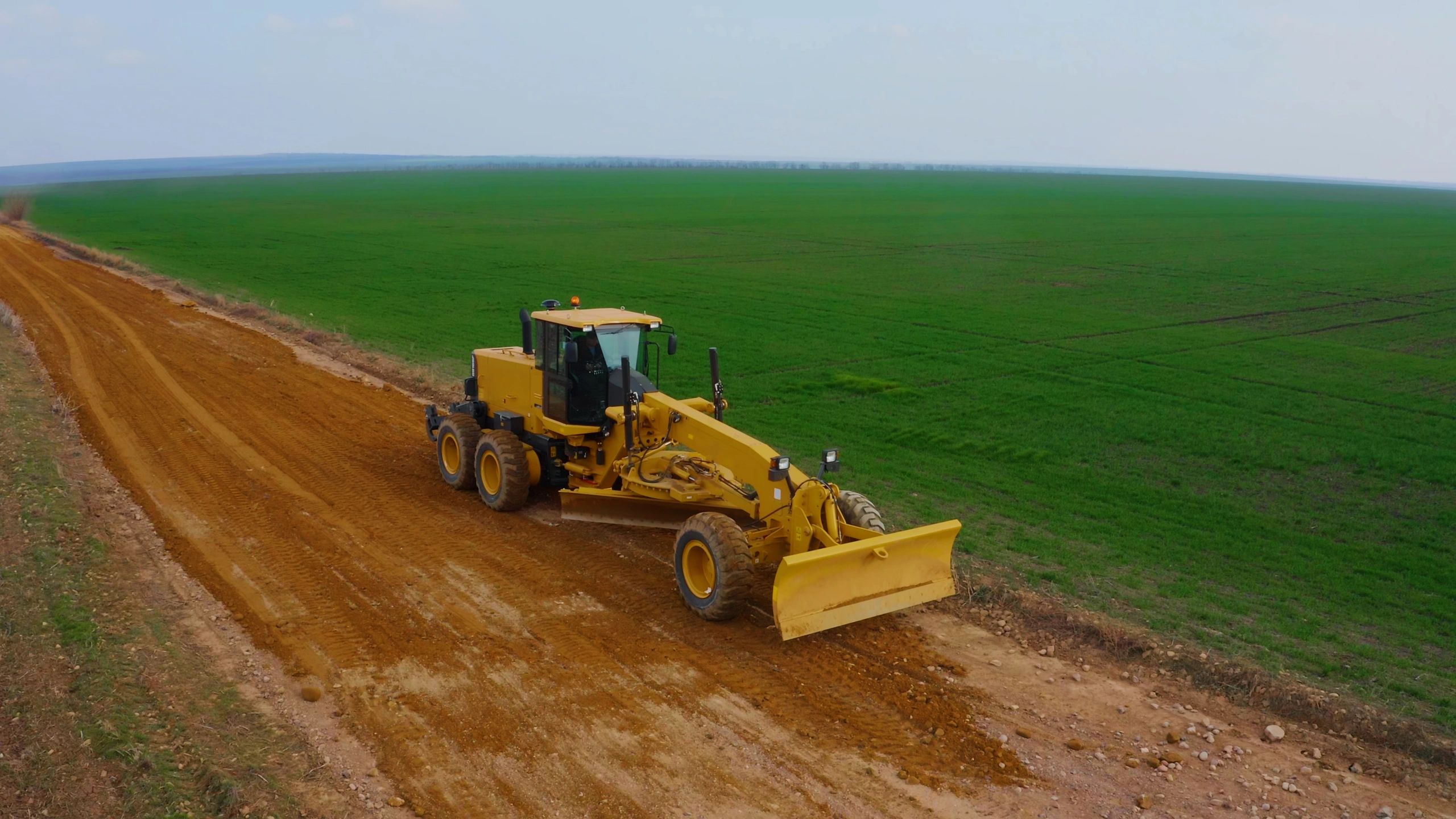 Heavy equipment shaping roadway and drainage grade